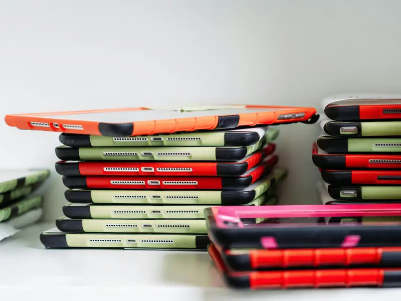 Stacks of iPads and tablets in cases waiting for repair